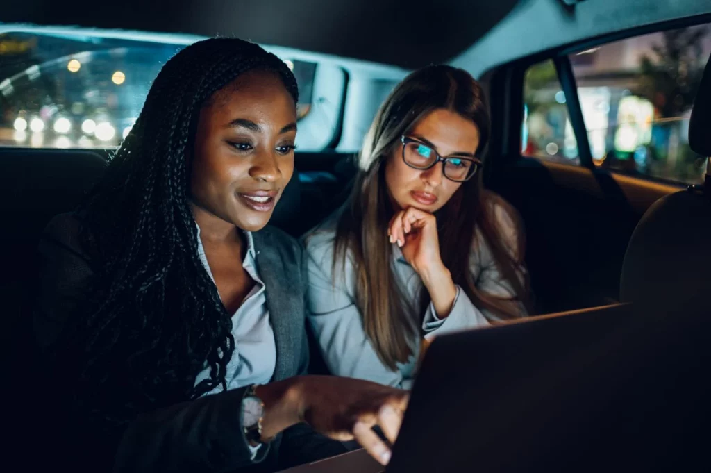 Deux femmes consultent un ordinateur portable à l'arrière d'une voiture